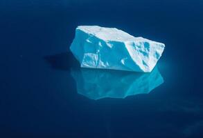 An iceberg floating in the ocean with a blue sky photo