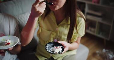 Handheld zoom out shot, Three friends are enjoy a cake on a sofa in a warmly decorated room at home. Share special moments together at home video