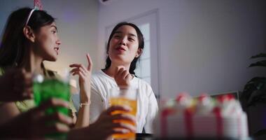 Handheld low angle view shot, Three young women chatting happily, enjoying snacks and drinks at their small party. video
