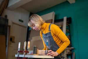 Female carpenter turn wood on lathe, shape custom pieces in workshop. Skilled labor, custom orders photo