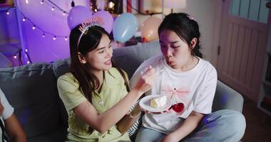 Handheld high angle view shot, Three friends are enjoying a cake on a sofa in a warmly decorated room at home. Share special moments together at home video