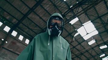 Person in safety chemical suit looks at camera. Portrait of a human in gas mask on ruined building background. View from below. Polluted zone. High level of radiation. video
