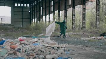 sobrevivente corrida dentro abandonado lugar. humano dentro protetora terno e gás mascarar com pano corre loucamente dentro arruinado construção em lixo fundo. video