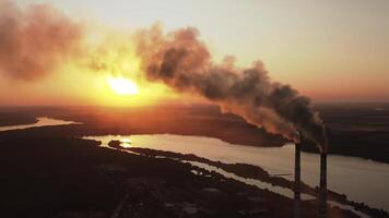 Massive air pollution near the river at darkness. Huge puffs of harmful smoke exhaust into the air against setting sun. Chimneys with dark fumes from manufacture. Aerial view. video