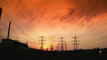 Red sunrise with power lines. Hydro transmission lines and towers making up the electricity grid. Panoramic view of eletric towers at sunset. Motion camera back. video