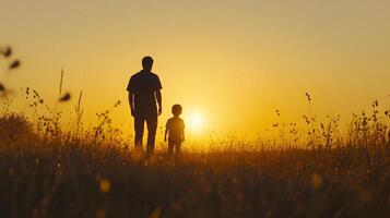 A man and child walking in a field at sunset photo