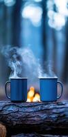 Cozy autumn moment with enamel mugs of hot tea on rustic wood by campfire photo
