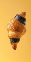 Levitating charcoal croissant on gradient background for creative design photo