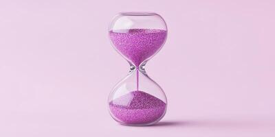 Elegant glass hourglass with metallic pink glitter grains on pastel background for time concept decor photo