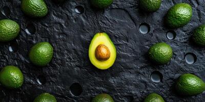 Fresh avocados flat lay on black slate background for culinary and food design photo