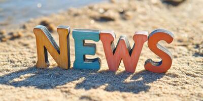 Summer beach scene with painted wooden letters spelling NEWS for creative design and print use photo