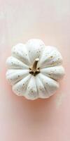 Close up of perfectly shaped tiny white pumpkin against pastel background photo
