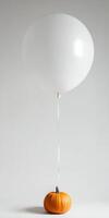 Elegant matte white balloon tethered to pumpkin for minimalist decoration and festive display photo