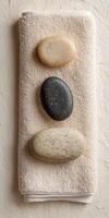 Spa wellness concept with rolled towel, massage stones, and herbal compress photo