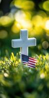 Patriotic memorial symbol with cross and American flag in sunlit grass setting photo