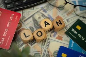A wooden blocks with the word PROFIT written on it is surrounded by several credit cards, sunglasses and a black calculator, and underneath are several dollar bills. concept of business and finance. photo