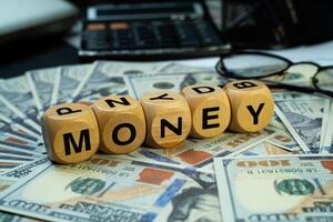 wooden block with MONEY written on it, arranged on top of several dollar bills, with an eye level view. Business and financial backgrounds. photo