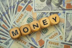 Several hundred dollar bills on the table with a wooden block with MONEY written on it. This image is ideal for use in business and financial backgrounds. photo