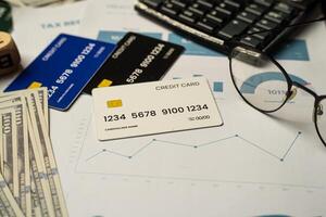 Top view of a realistic credit cards, hundred-dollar bills, performance charts, and a keyboard. The image evokes themes of financial literacy, digital payment systems, and economic analysis. photo