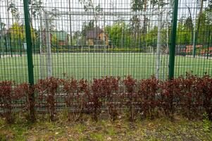 soccer field behind the fence, football field with goals and white lines on the grass, surrounded by a green net, a fence around a football field in the form of an iron net with large cells. photo