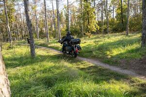 A man riding a motorcycle on a trail through a forest photo