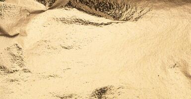 gold foil texture with soft creases and reflective highlights, creating a luxurious and abstract photo