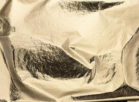 Gold metallic foil texture. Crumpled, shiny, and glossy surface with creases and folds. Elegant, photo