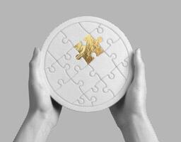 Golden puzzle piece in the shape of a circle, held in hands, symbolizing unity, connection, and photo
