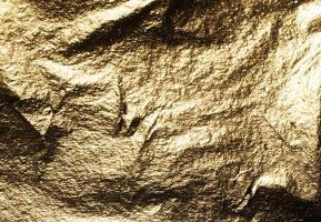 Golden foil with crumpled, metallic texture creates a dramatic, reflective surface. Shiny, embossed photo