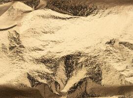 Lustrous golden foil with intricate folds and a slightly distressed surface, creating dynamic photo