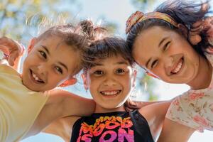 Close up face of happy children embracing each other and smiling at camera, group of joyful kids playing together outside. photo