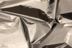 Silver foil with shiny, metallic texture creates a reflective, polished surface. Crinkled, folded photo