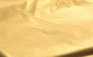 Gold metallic foil texture with a smooth, creased surface. Shiny, reflective material in warm yellow photo