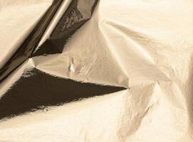 Gold foil texture with a crinkled, shiny surface. Elegant vintage metallic material with a sleek, photo