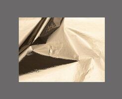Golden rectangular shape with a polished, metallic surface creates a sleek, modern design. Wrinkled photo