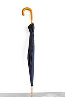 Typical black umbrella closed and isolated on white background isolated photo