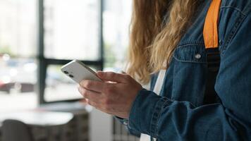 Closeup of male student hands typing on smartphone in university hallway unrecognizable man guy texting message mobile phone browsing online content indoors communication education modern technology photo