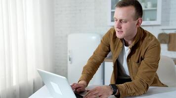 Young man speaking online. Freelancer male working with clients in front of a laptop. Student having a call while sitting at home. Distant job. video