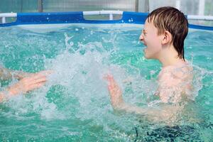 boy splashing on summer pool having fun activity photo