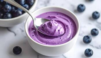 Creamy blueberry yogurt in white bowl with fresh blueberries on marble surface photo