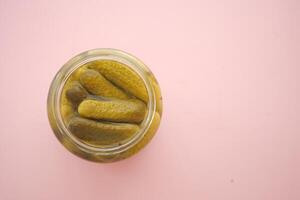 Pickles in a jar on pink surface photo