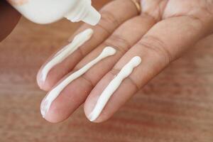 Applying sunscreen cream to fingers for skincare routine photo