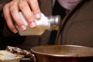 Adding salt to enhance the flavor of a freshly prepared dish photo