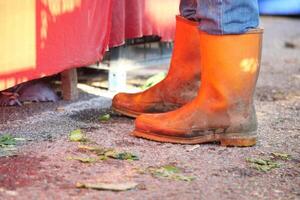 Bright orange boots on muddy ground near market stall photo