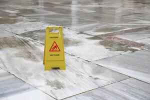 Caution sign placed on wet floor in a public area photo
