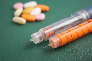 Insulin injection pen for diabetics and medical pills on table photo