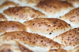 Freshly baked rolls with sesame seeds in detail photo