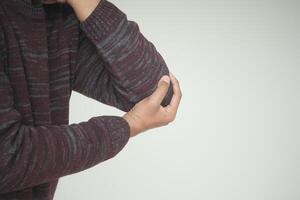 Person experiencing discomfort while holding elbow in casual setting photo