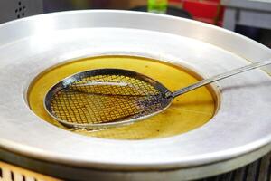 Frying pan with a skimmer tool in a street food vendor's kitchen photo