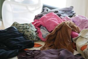 Clothes piled on a table in a bright room during the day photo